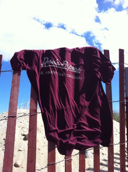 Dan's Papers T-shirt on a fence on the beach