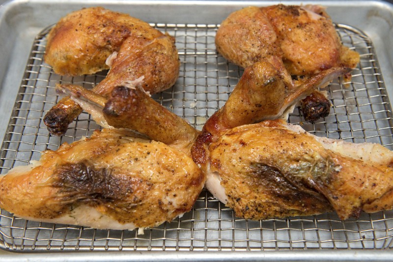 The chickens out of the oven and carved into quarters, sprinkled with coarse salt ready for plate.
