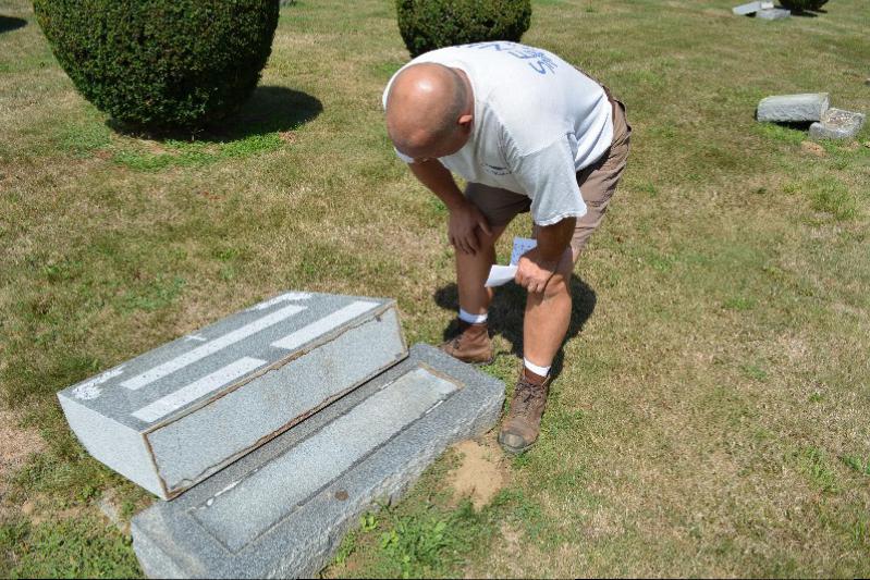 Eric Wright examines a headstone at neighboring Sacred Hearts cemetery