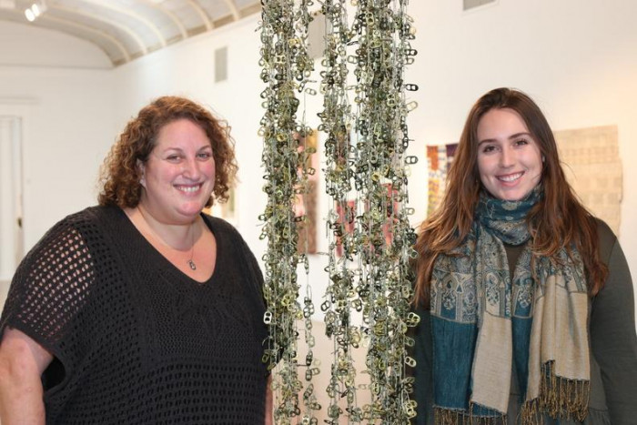 Southampton Arts Center Director of Programs Amy Kirwin and Administrative Assistant at SAC Hannah DiGate pose next to an art piece currently on display for "A Radical Voice: 23 Women"
