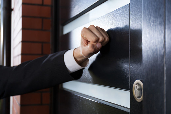 Process server hand knocking on door