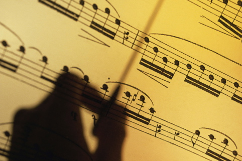 Silhouette of a hand conducting over sheet music