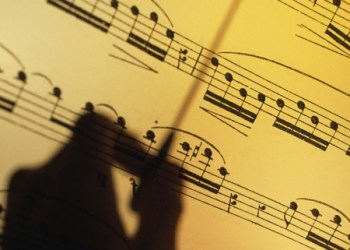 Silhouette of a hand conducting over sheet music
