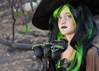 Little witch holding black roses looking away