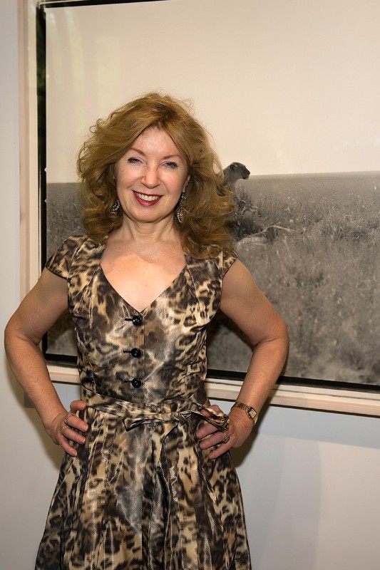 Get Wild host April Gornik in front of a large photograph of a lion, part of the evening's auction art.