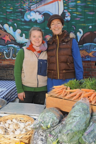 Karin Bellemare (Sunset Beach Farm) and Ana Nieto (Fair Foods Farmers Market Manager) in front of BayBurger's famous mural Blurb: The famous Sag Harbor Farmers Market has made its annual end-of-season move to its off-season location next to BayBurger in Sag Harbor