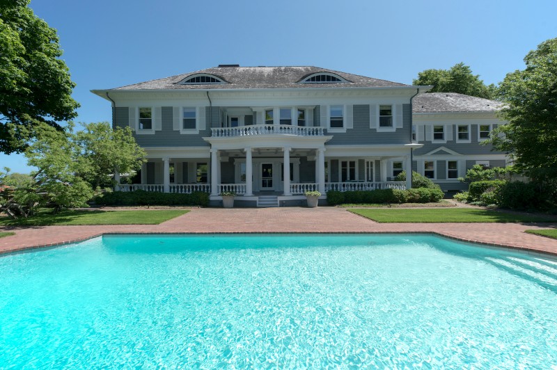 The pool side of this 7-bedroom Georgian-style 1900s residence is surrounded by the waters of Mecox Bay.