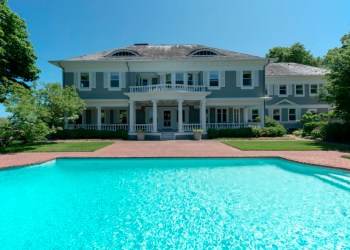 The pool side of this 7-bedroom Georgian-style 1900s residence is surrounded by the waters of Mecox Bay.
