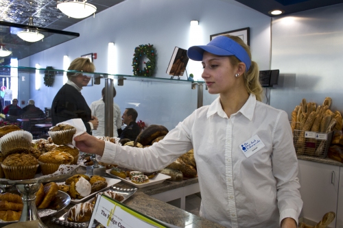 Savannah Kurz puts freshly baked muffins on display during the Blue Duck Bakery Cafe's grand-opening weekend in downtown Riverhead.