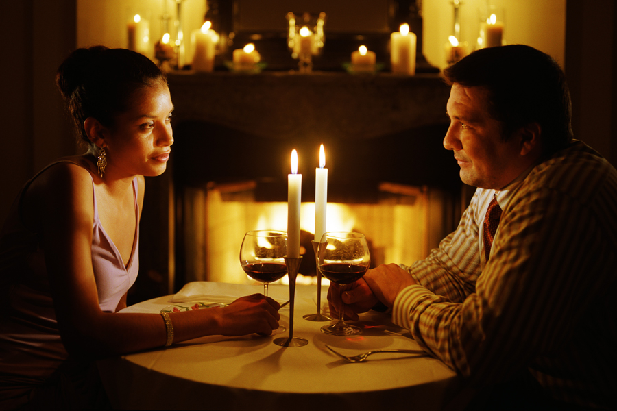 Couple sitting at candle lit table next to fire