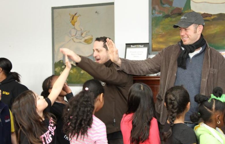Chef Jason Weiner of Almond Restaurants and Sean Barrett founder of Dock to Dish high five the students as they assemble on line for their lunch