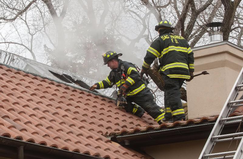 Sag Harbor firefighters vent the roof by smashing a skylight with an axe.
