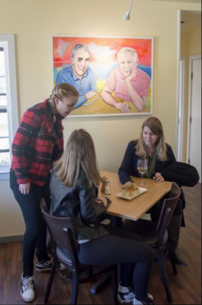 Suter women, sisters Charlotte and Olivia with their mother Cathy, sample Estia's Little Kitchen hors d'oeuvres beneath a painting of Peter Matthiessen and James Salter by their sister Valerie Suter.