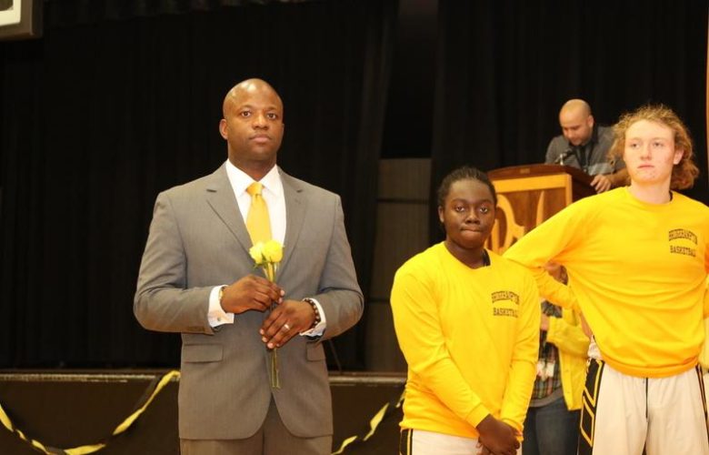 Head coach Ron White leads by example as he helps his team present yellow roses to each graduating cheerleader
