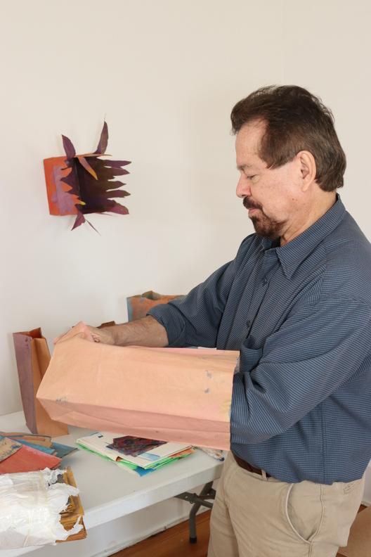 Artist Francisco Alvarado-Juarez demonstrates how the completed paper bags will be assembled and displayed for the exhibition this fall