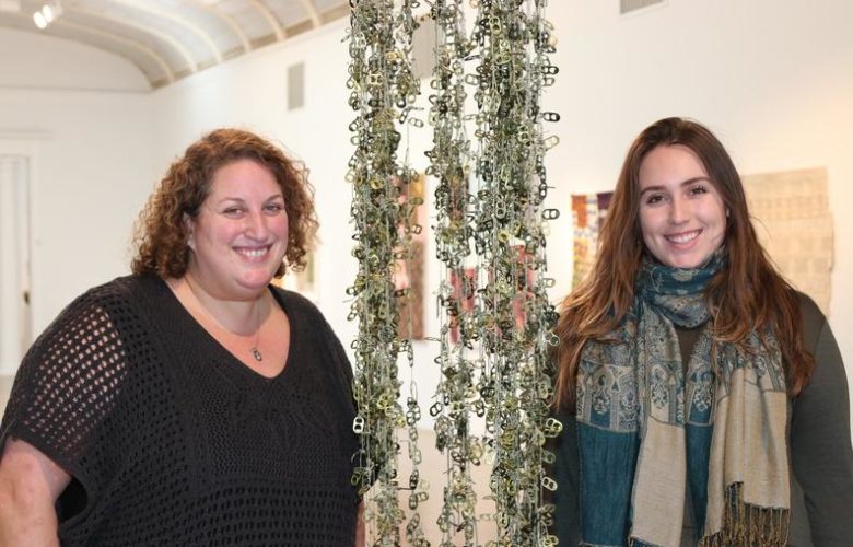 Southampton Arts Center Director of Programs Amy Kirwin and Administrative Assistant at SAC Hannah DiGate pose next to an art piece currently on display for "A Radical Voice: 23 Women"