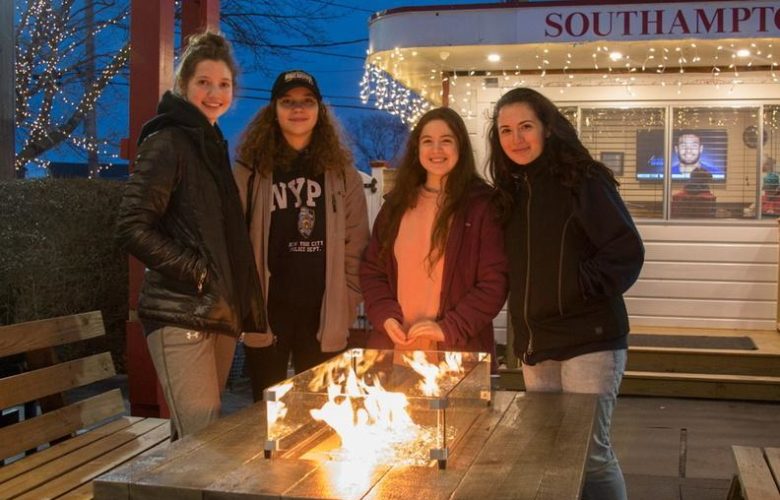 Fiona Joseph, Elissa Caufield, Emery Vogel and Clair Padola get warm by the fire.