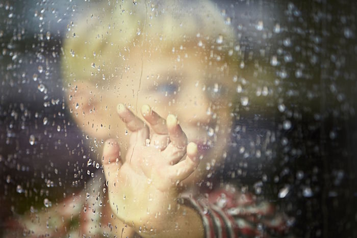 33723258 – little boy behind the window in the rain – selective focus