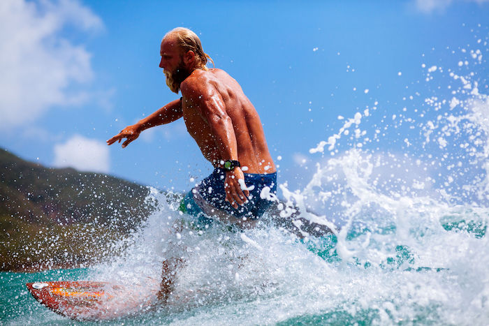 man with beard surfing wave splash actively
