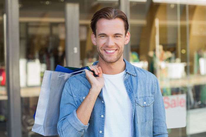 portrait of a smiling man with shopping bags at the mall