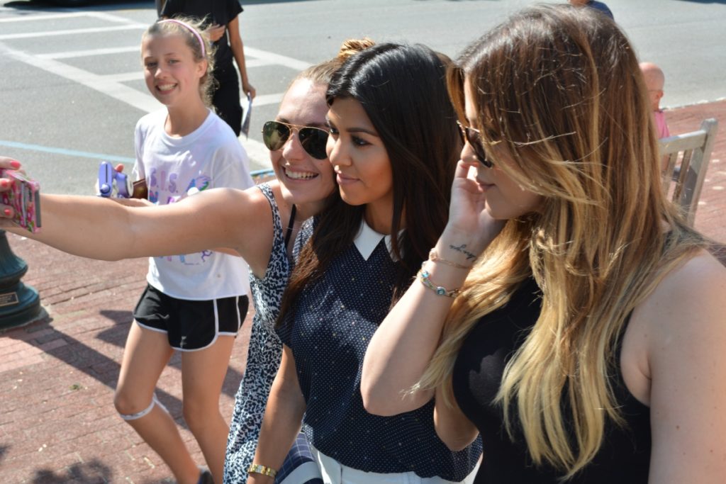 A fan takes a selfie with the Kardashian sisters on Main Street in Southampton Village.