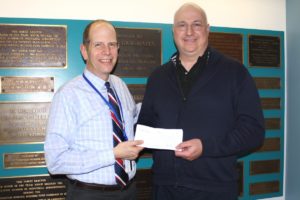 Southampton Hospital President and CEO Robert S. Chaloner accepts a check from Hamptons Health Society Chairman Peter Michalos.