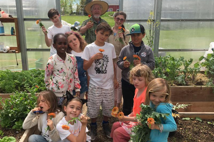 Jon Snow and children from the Hayground School in their garden greenhouse