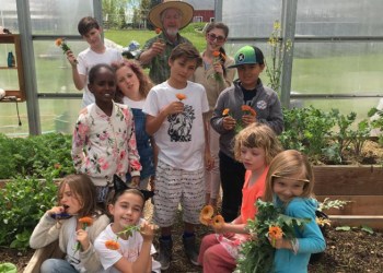 Jon Snow and children from the Hayground School in their garden greenhouse