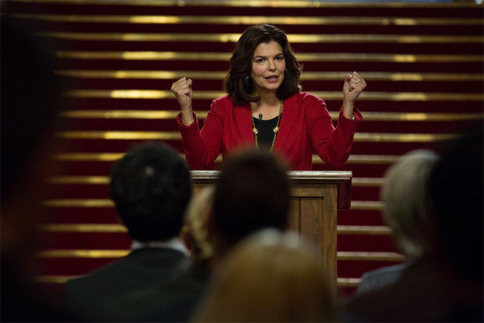 Actress Jeanne Tripplehorn as Charlotte Wells standing at a podium with her fists up in "Little Pink House,"