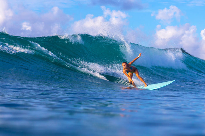 Surfer girl shredding big blue wave