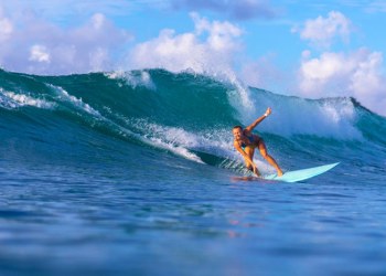 Surfer girl shredding big blue wave