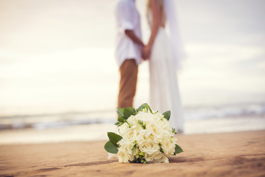 Just married couple holding hands on the beach