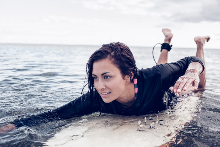 Young woman swimming over surfboard in water