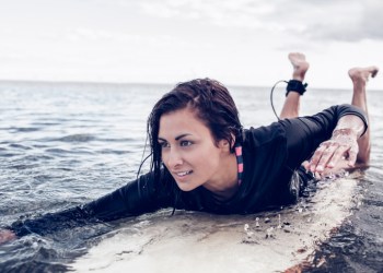 Young woman swimming over surfboard in water