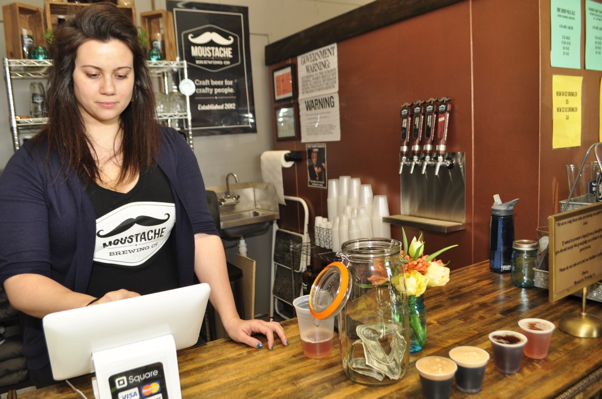 Kim Corbett, of Bay Shore, tended bar and rang up retail sales at the private soft opening of Moustache Brewing Company, which took place Sunday afternoon on Hallett Street in Riverhead. Corbett, the sister of co-owner Lauri Spitz, said their family could not be more proud of what Lauri and husband, Matt, have accomplished in opening the brewery.