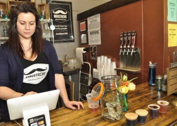 Kim Corbett, of Bay Shore, tended bar and rang up retail sales at the private soft opening of Moustache Brewing Company, which took place Sunday afternoon on Hallett Street in Riverhead. Corbett, the sister of co-owner Lauri Spitz, said their family could not be more proud of what Lauri and husband, Matt, have accomplished in opening the brewery.