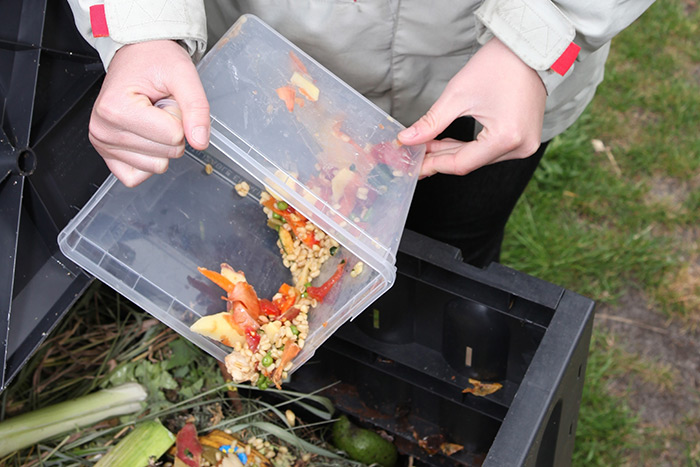 hands dumping food garbage into a composter