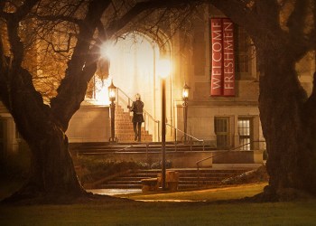 A female college student walking into a building late at night, with a welcome freshman banner hanging above - from the poster for the film 