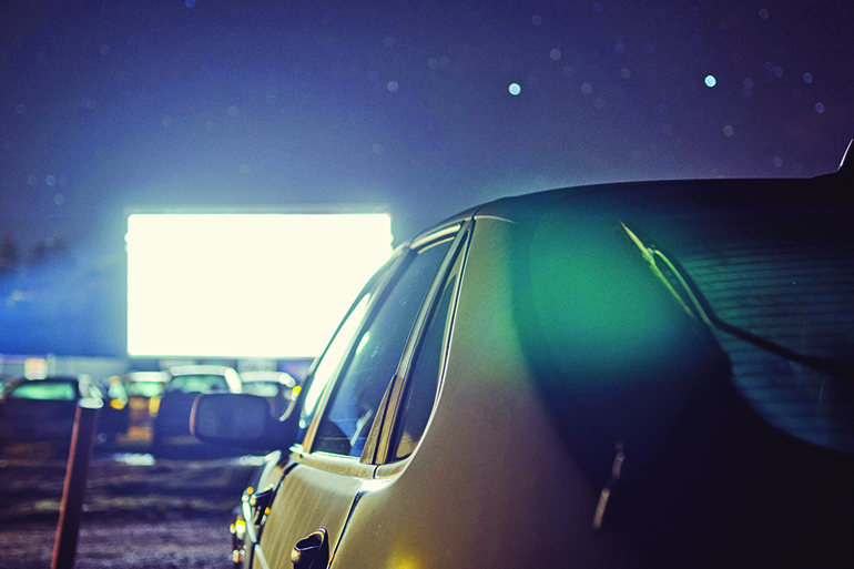 A parked car at a drive-in movie theater