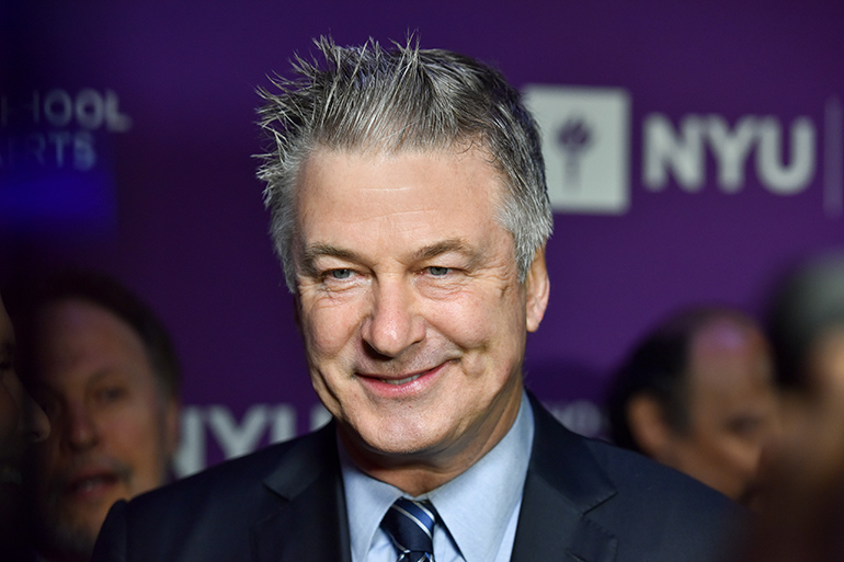 Alec Baldwin smiling with purple background at NYU Tisch School of the Arts Gala in 2018