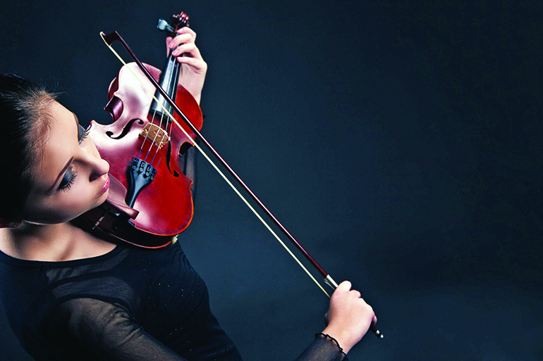 27011648 - beautiful young woman playing violin over black background