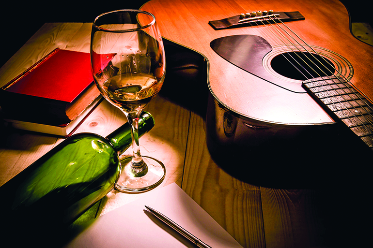 43657083 - guitar with red book and wine on a wooden table.