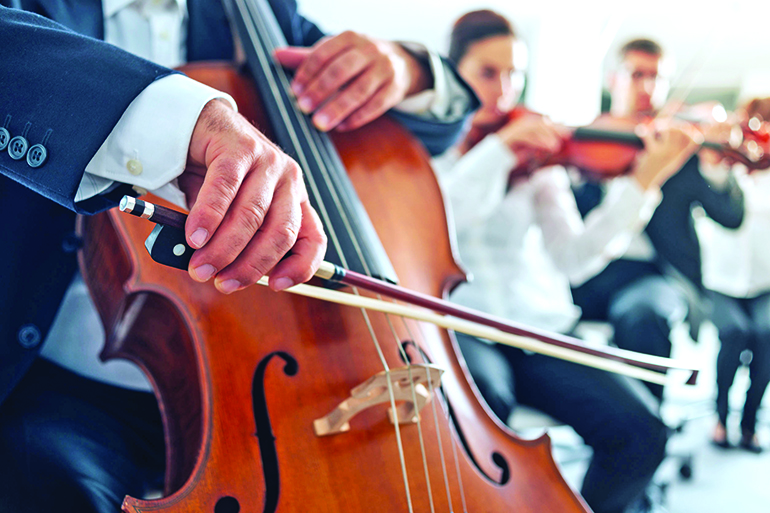 46506738 - professional cello player's hands close up, he is performing with string section of the symphony orchestra