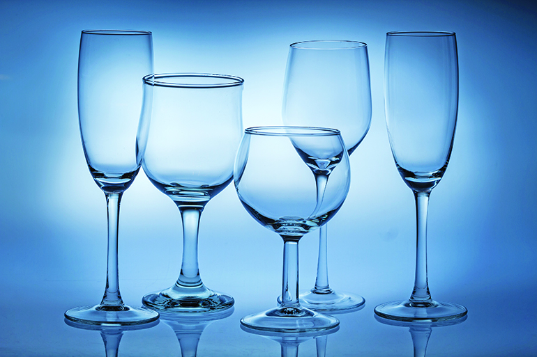 Different types of empty glasses on a blue background.