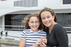 Eva, age 12, and Emma, age 13, are all smiles as they looked at the yachts in the harbor