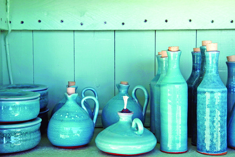 14764964 - turquoise glazed ceramic pitchers in green shelf , crete , greece