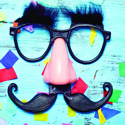 72526326 - closeup of a pair of fake black glasses with eyebrows, a nose and a mustache forming the face of a man on a blue rustic wooden surface full of confetti