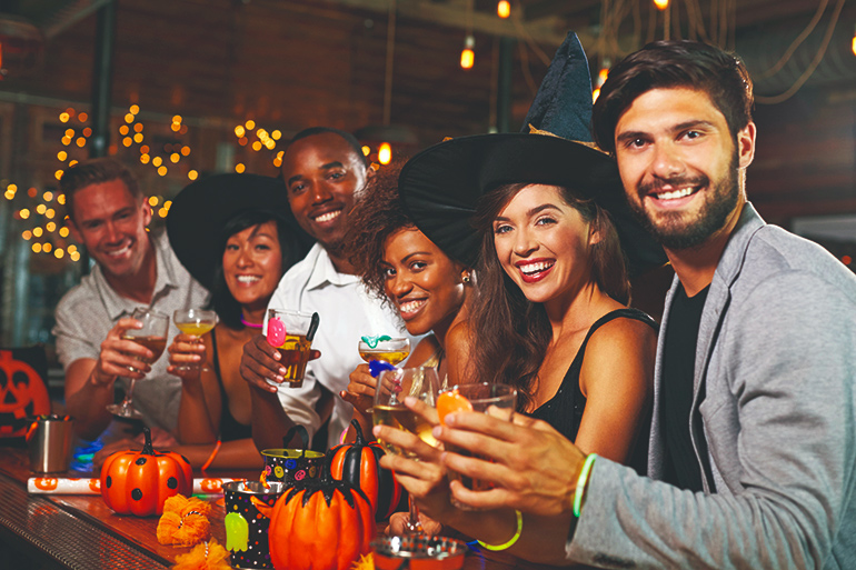 Friends enjoying a Halloween party at a bar look to camera