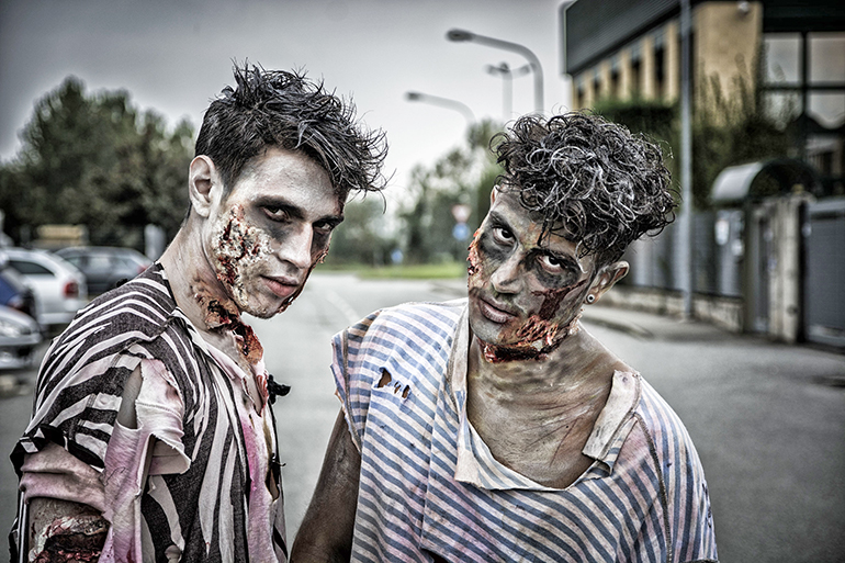 Two male zombies standing in empty city street looking at camera