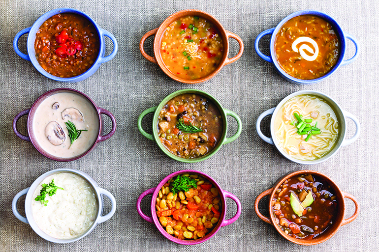 50249960 - assorted soups from worldwide cuisines displayed in bowls in three colorful lines garnished with cream and herbs in a world of soup concept, overhead view